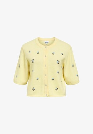 Kollane kardigan lühikeste varrukatega, millel on sinistes ja rohelistes broderiõitega lilled. Viis nööpi ja ümar kaelus lisavad detaili.