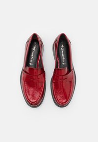 Mocassins de pele vernizada vermelha com ponta arredondada e uma faixa decorativa. Sola e interior em borracha preta. Tamanho 37. Textura suave.