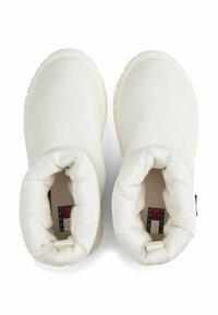 Botas de tobillo acolchadas en blanco con una suave textura acolchada y una punta redonda. Cuenta con una etiqueta de logo en el interior y una suela de goma flexible.