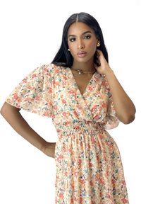 Robe à motifs floraux avec de courtes manches flottantes, un décolleté en V profond et une taille smockée. Fabriquée en tissu léger dans des teintes pastel.