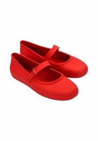 Bailarinas rojas de goma suave. Presentan una punta redonda, una correa a lo largo del empeine y un forro interior suave.