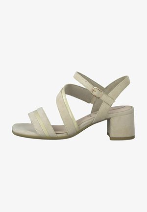 Beige suede block-heeled sandals with cross straps and a buckle. Features smooth texture and minimalistic design.