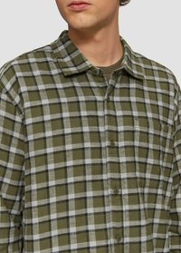 Groene en witte geruite flanellen shirt met een zachte textuur, knoopsluiting en een kraag. Heeft een borstzak en contrasterende zwarte lijnen.