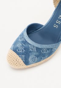 Denim espadrille med en lyseblå overdel som har et teksturert mønster og en beige vevd jute tåhette. Støtter slip-on design.