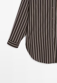Brown gestreepte lange mouwen shirt met witte verticale strepen, met een afgeronde onderrand en knoopsluitingen aan de voorkant.