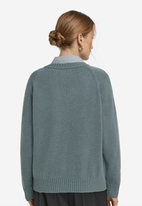 Hellblau-grüner Pullover mit strukturiertem Strick, geripptem Saum und oversized Passform. Verfügt über einen Rundhalsausschnitt und Raglanärmel.