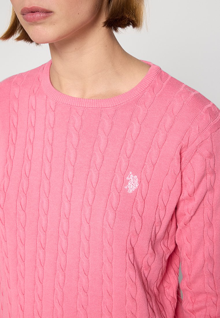 Rosa Kabelstrickpullover mit rundem Ausschnitt und subtiler Logo-Akzentuierung im linken Brustbereich. Hergestellt aus weichem, strukturiertem Stoff.