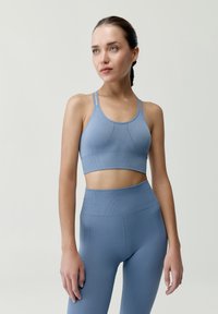 Svetlomodrá športová podprsenka s nastaviteľnými tenkými ramienkami, textúrovaným ribbingom a malými diamantovými vzormi; skombinovaná s vysokými legínami v rovnakom odtieni.