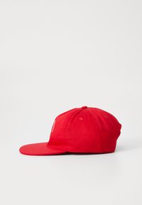 Punane pesapalli müts, mis on valmistatud puuvillast, lame äärega ja reguleeritava nööbiga. Lihtne disain, ilma nähtavate mustrite või logodeta.