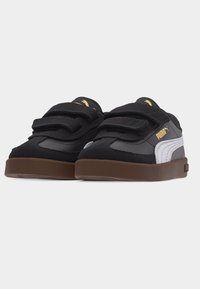 Μαύρα και γκρι αθλητικά παπούτσια Puma με λευκή ρίγα στο πλάι, καφέ σόλα και δύο μαύρα λουράκια με βέλκρο, παρουσιάζονται πάνω σε ανοιχτογκρι φόντο.