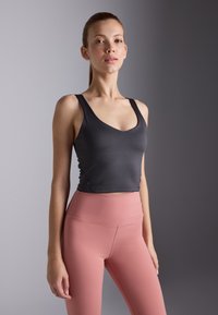 Must mustriga mustriga tank top laia rihmade ja v-kujuga, kombineeritud kõrge vöökohaga roosade leggingsitega, mis on valmistatud siledast ja elastsetest materjalidest.
