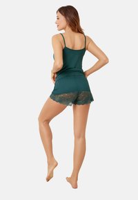 Zestaw topu na ramiączkach i szortów w kolorze zielono-niebieskim z koronkowym wykończeniem na szortach, charakteryzujący się dopasowanym krojem i ramiączkami spaghetti dla wygodnego dopasowania.