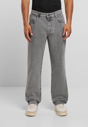 Hallid teksapüksid lõdva lõikega, viie taskuga ja nähtava õmblusega. Kandatud valgete ja beežide vabaajajalatsitega.