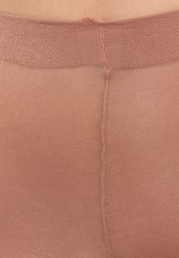 Rajstopy w kolorze cielistym o gładkiej fakturze, wykonane z lekkiego materiału, z wzmocnionym pasem i ozdobionym środkowym szwem.