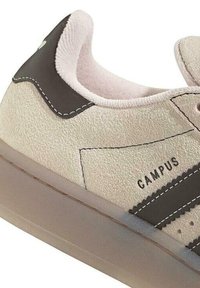 Basket beige en suède avec des accents marron foncé, semelle en caoutchouc et détails brodés. Présente le texte "CAMPUS" sur le côté. Design à bout rond.