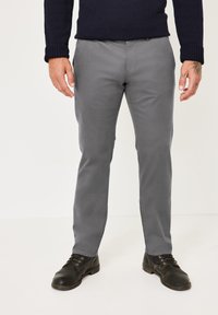 Graue Baumwollhosen mit schmalem Bein und geradem Schnitt, ausgestattet mit vorderen Taschen und einer glatten Textur. Kombiniert mit schwarzen Lederschuhen.