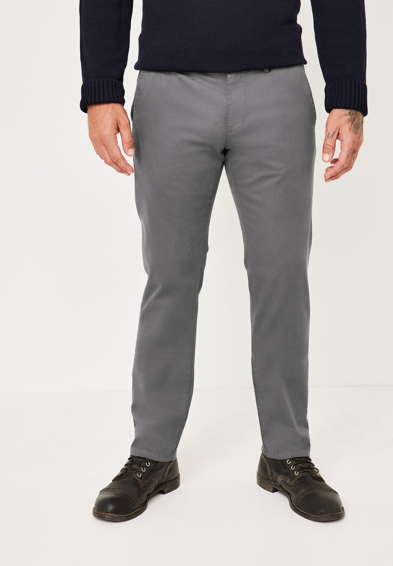 Graue Baumwollhosen mit schmalem Bein und geradem Schnitt, ausgestattet mit vorderen Taschen und einer glatten Textur. Kombiniert mit schwarzen Lederschuhen.