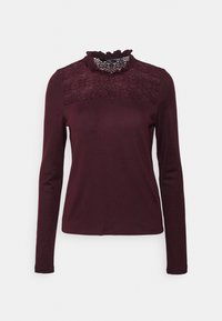 Top a maniche lunghe color bordeaux con un pannello in pizzo e un colletto finto arricciato. Tessuto morbido con leggera elasticità e silhouette aderente.