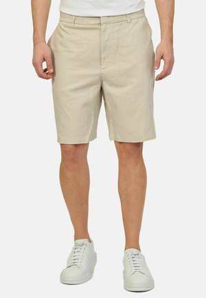 Bermuda in cotone beige con vita elastica, tasche laterali e vestibilità comoda. Abbinati a sneakers bianche per un look casual.