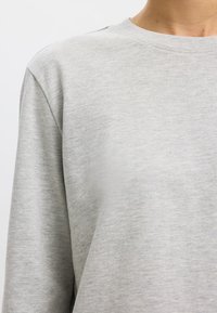 Lichtgrijze sweatshirts van zacht materiaal, met een ronde hals en een comfortabele pasvorm. De structuur is glad met minimale stikseldetails op de schouders.