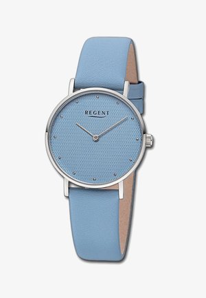 Montre ronde avec un cadran texturé bleu clair, des accents en argent et des marqueurs d'heure. Terminée par un bracelet en cuir bleu clair assorti.