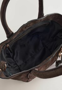 Barna velúr bevásárlótáska dupla fogantyúkkal. A belsejében fekete textil bélés és cipzáras zseb található, egyszerű, mégis funkcionális kialakítással.