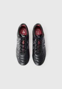 Chaussures de sport noires avec une tige en cuir lisse et texturé, présentant des accents rouges, un logo gris et un design de bout arrondi. Comprend des lacets noirs.