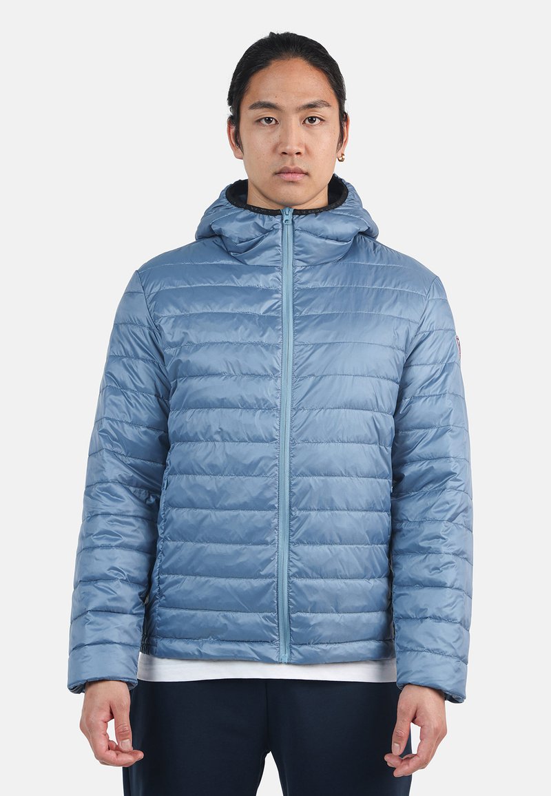 Giacca puffer azzurra chiara con cappuccio, caratterizzata da sezioni trapuntate orizzontali, zip a tutta lunghezza e due tasche laterali. Texture liscia e lucida.