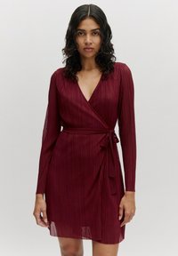 Bordeaux wikkeldress met lange mouwen, v-hals en verticale plooien. Gemaakt om de taille met een bijpassende stoffen riem. Zachte, gestructureerde stof.