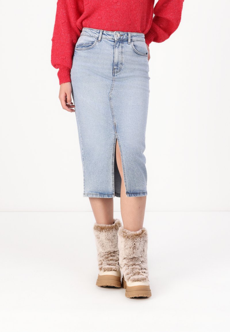 Ljusblå denim midi kjol med en fram slit, parat med beige stövlar med pälsfoder. Kjolen har en åtsittande design och klassiska fickor.