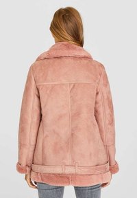 Roze nepbonten jas met een kraag, een gestructureerde afwerking en horizontale naden. Voorzien van een tailleband en een zachte, pluizige voering.