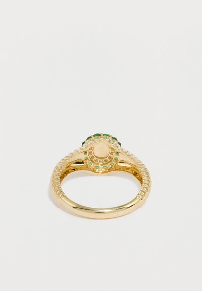 Χρυσό δαχτυλίδι με κεντρική κρεμ πέτρα περιβαλλόμενη από πράσινες λεπτομέρειες και μικρότερες πέτρες. Υφή στη μπάντα με περίπλοκες λεπτομέρειες.