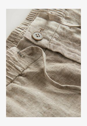 Ljust brunt linne tyg med synlig struktur, som har en texturerad knapp och en tyglina. Designen inkluderar ett elastiskt midjeband.