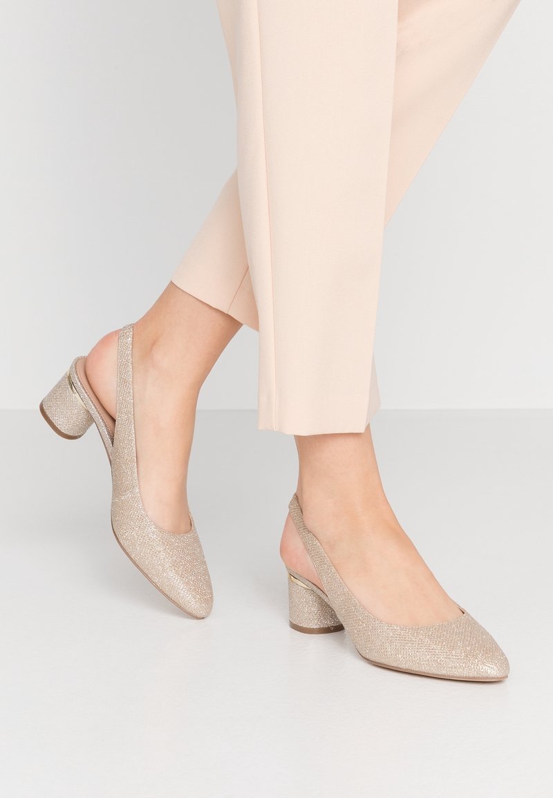 Kultaiset kimaltavat slingback-kengät, joissa on terävä kärki ja paksu lohkokorko. Tekstuuroitu kangas, jossa on hienovaraisia kimalluskorostuksia.