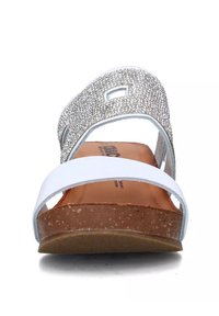 Ciabatta bianca con una striscia argentata brillante, plantare in sughero e suola testurizzata. Presenta dettagli con ritagli e fibbia regolabile per una vestibilità ottimale.