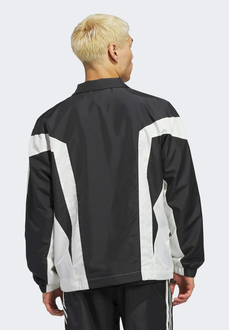 Schwarz-weiße Windbreaker-Jacke mit schlankem Design, elastischen Bündchen und kontrastierenden Paneelmustern auf dem Rücken. Leichter Stoff.