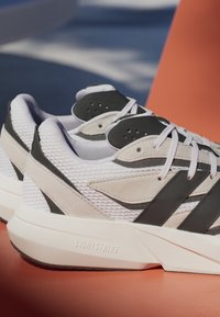 Running shoes with a white mesh upper, gray accents, and a textured black overlay. Features a LIGHTSTRIKE midsole for cushioning.