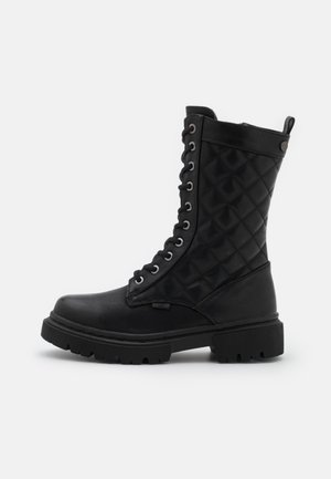 Botte noire mi-mollet à lacets avec dessus matelassé, semelle épaisse à relief et languette à l'arrière, vue de profil sur fond blanc.