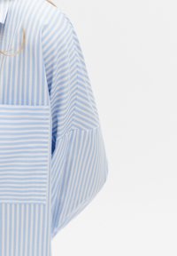 Lichtblauw en wit gestreept shirt met een grote borstzak, korte mouwen en een zachte, gladde textuur. Accentueert door contrasterende strepen.