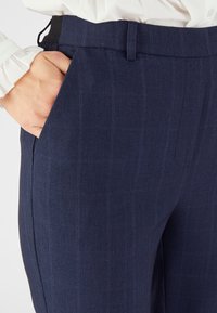 Navyblauwe broek met een subtiel ruitpatroon, voorzien van zijzakken, een strak design en een gladde stoftextuur.