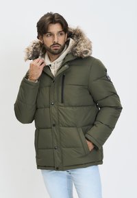 Oliven grøn pufferjakke med en faux fur-fodret hætte, lynlås-forsænket brystlomme og ribbede manchetter. Har en quiltet mønster og trykknapper.