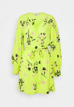 Heldere limoengroene jurk met lange mouwen, zwart en roze bloemenpatroon, knopen aan de voorkant, V-hals en tailleceintuur.