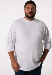 Langärmliges weißes T-Shirt aus weichem Stoff, mit rundem Halsausschnitt und kleinem, geprägtem Logo auf der Brust. Klassische Passform.