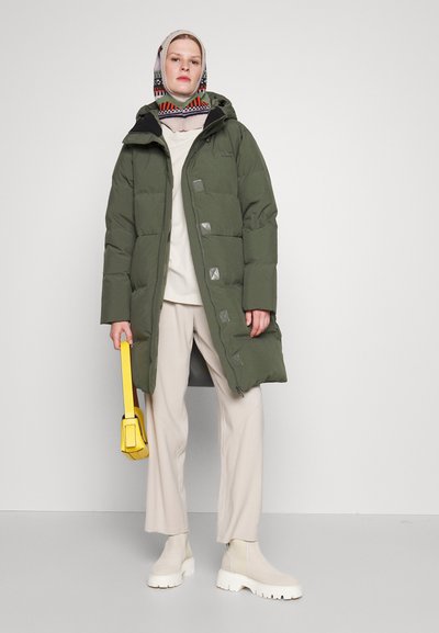 Olive green puffer coat with a hood, featuring silver hardware, a zip closure, and snap buttons. Paired with cream pants and yellow bag.