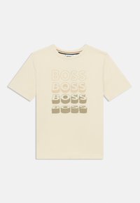 Μπλουζάκι από βαμβάκι σε κρεμ απόχρωση, με τη λέξη «BOSS» τυπωμένη σε διάφορες αποχρώσεις και μεγέθη στο μπροστινό μέρος. Στρογγυλός λαιμός και κοντά μανίκια.