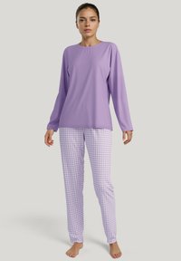 Lavendel lange mouwen top gecombineerd met geruite lavendel en witte pyjamabroek. Zachte stof, losse pasvorm en subtiele patroondetails.