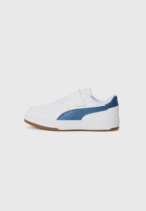 Hvid sneaker med en blå accentstripe, der har en tekstureret overflade, polstret krave og velcrorem. Gummisål, lavtop design.