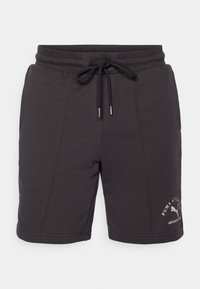 Sorte treningshorts laget av myk stoff med elastisk midje, snorer i lukking og brodert logo-detalj på siden.
