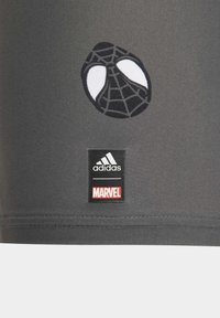Maglietta sportiva grigia con un logo Spiderman in bianco e nero e etichette del marchio Adidas e Marvel all'orlo. Tessuto liscio e elasticizzato.