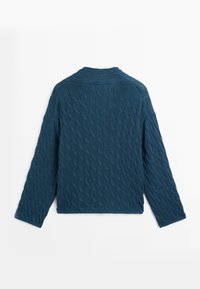 Pull en maille torsadée bleu marine à manches longues et col rond, montré de dos sur un fond blanc.
